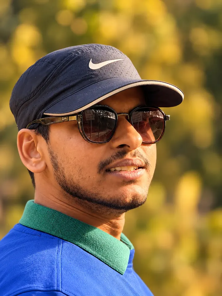 Faraz Ansari outdoors in a navy cap, sunglasses and a blue polo shirt with a green collar