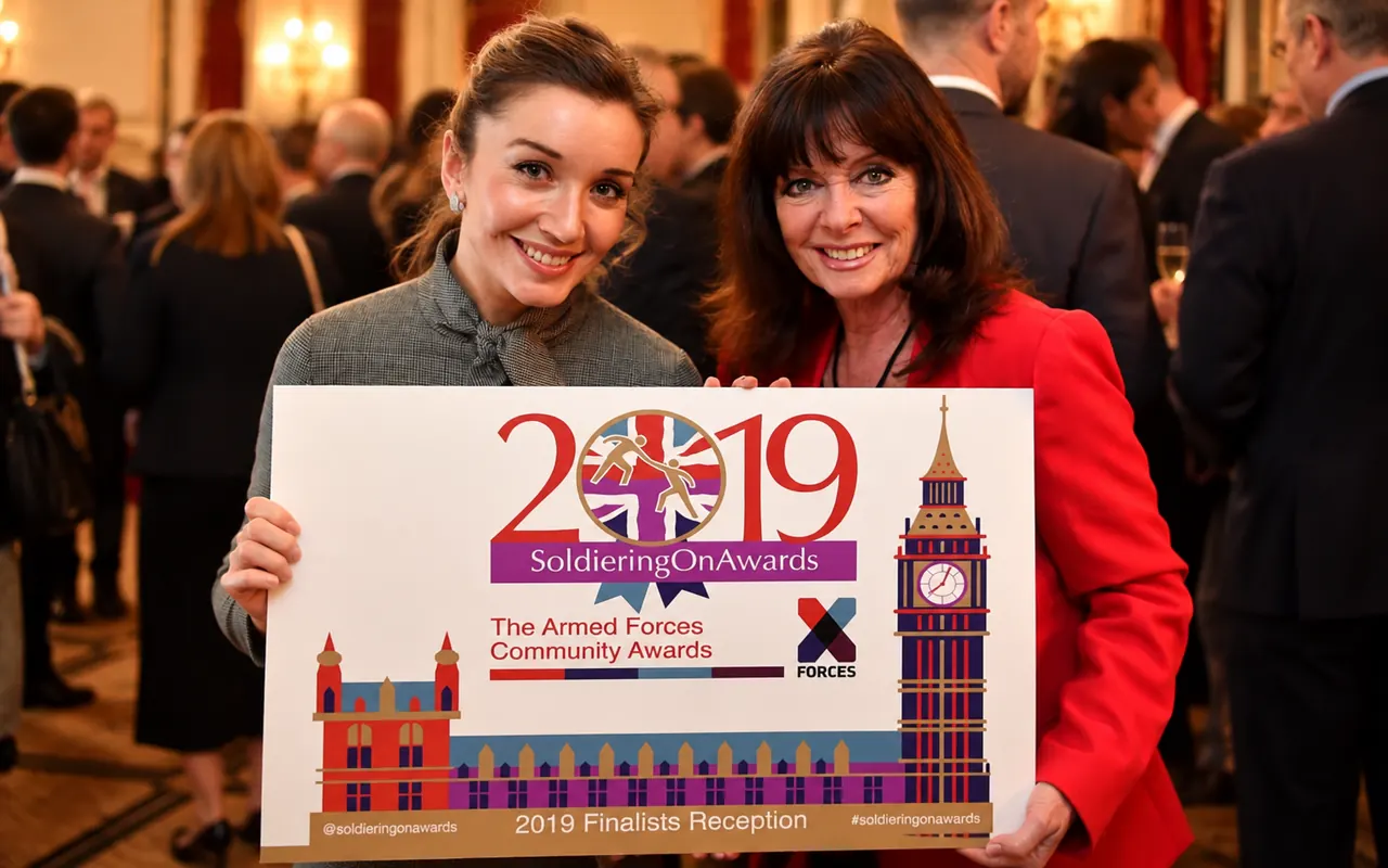 Two guests holding the Soldiering On Awards 2019 finalists reception sign, showing the original logo with Big Ben